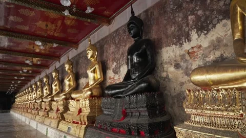 Black Buddha statue among a row of many golden statues sitting in a meditative 스톡 동영상 289800232
