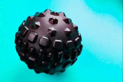 Black bumpy foam massage ball is a rubber ball on a blue background. 写真素材