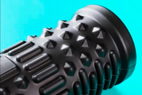 Black bumpy foam massage roller, body roller on blue background. F Stock Photos