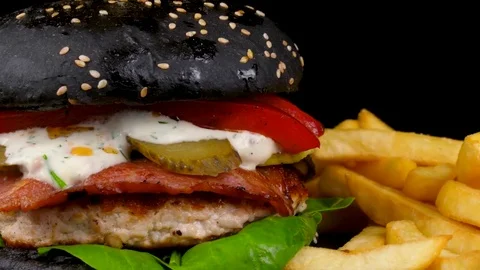 Black Burger with bacon and Fried Potato wedges, decorated with pepper corns Stock Footage 84652196