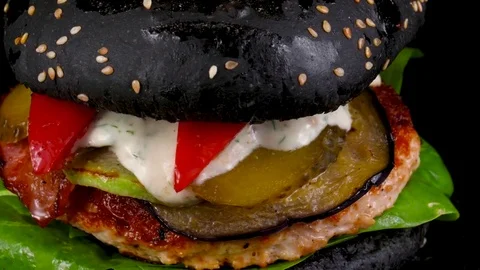 Black Burger with bacon, grilled vegetables and pickled cucumbers, close-up view Stock Footage 84652700