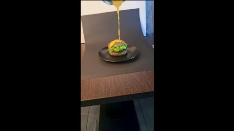 Black burger with beef patty, lettuce and sesame seed bun with cheese sauce Stock Footage 344844577