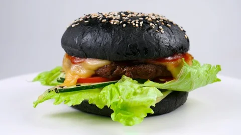 Black burger with fresh vegetables, served in restaurant Stock Footage 87790623