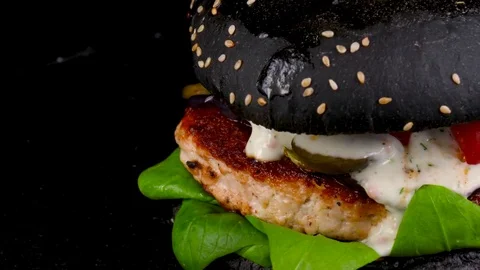 Black Burger with meat and bacon, grilled vegetables and pickled cucumbers Stock Footage 84652667