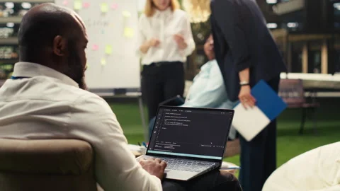 Black business professional coding on laptop near whiteboard Stock Footage 338383877