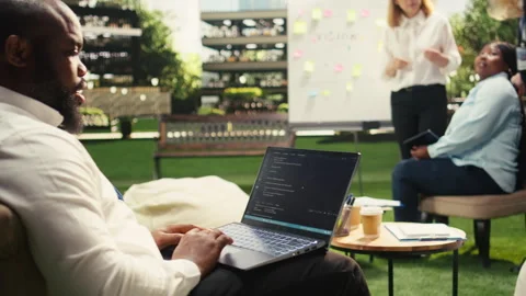 Black business professional coding on laptop near whiteboard Stock Footage 338388447