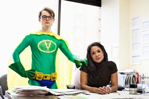 A black business woman at her desk with her caucasian office super hero advisor. Stock Photos