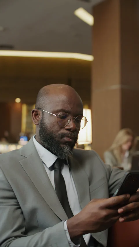 Black Businessman Checking Smartphone while Sitting in Modern Hotel Lounge Stock Footage 333630938