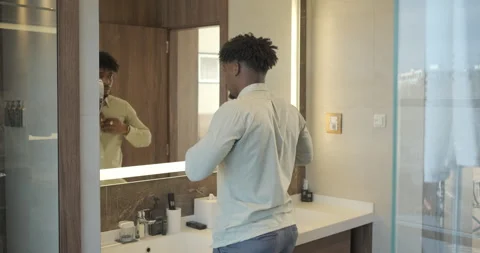 Black businessman getting ready for work while standing in bathroom in fron.. Stock Footage 329180597