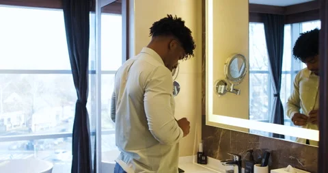 Black businessman getting ready for work while standing in bathroom in fron.. Stock Footage 336187295