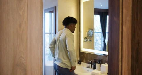 Black businessman getting ready for work while standing in bathroom in fron.. Stock Footage 336187446