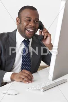 Black businessman talking on telephone at desk Stock Photos