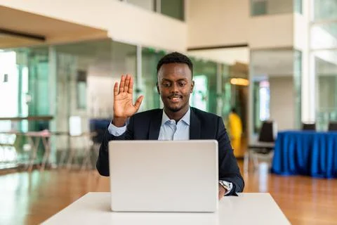 Black businessman using laptop computer in office while having video call Stock Photos