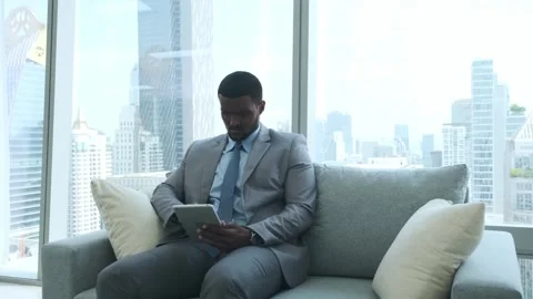 Black businessman using tablet working on sofa in office. Video stock 245749441