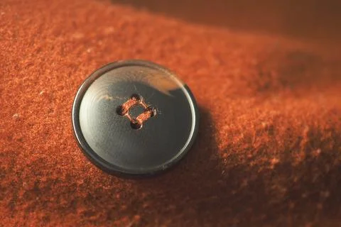 Black button on a brown fabric surface with soft texture Stock Photos