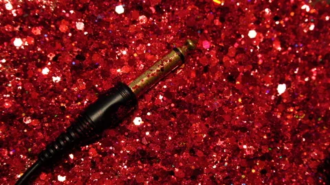 Black cable on the background of red glitter Vídeos de archivo 100012858