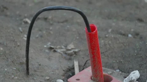 Black cable looping into red corrugated pipe on ground outside Stock Footage 337123278