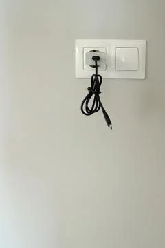 Black cable plugged into wall socket Stock Photos