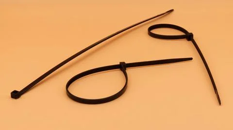 Black cable ties isolated on orange background. Plastic Tie Wraps. Stock Photos
