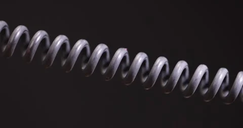 A black cable twisted in the shape of a spring for equipment, an old black cable Video stock 313582329