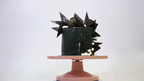 Black cake decorated rotates in a circle on a pink stand. Stock Footage 149959476