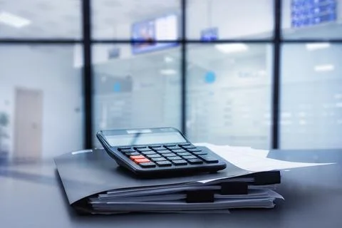 Black calculator on a stack of business documents and a dark folder in mode.. Stock Photos