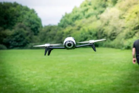 Black camera drone in flying with visible propellers movement in green field Stock Photos