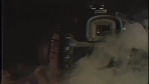 A black camera is spinning around in the darkness and a white smoke. Stock Footage 116062860