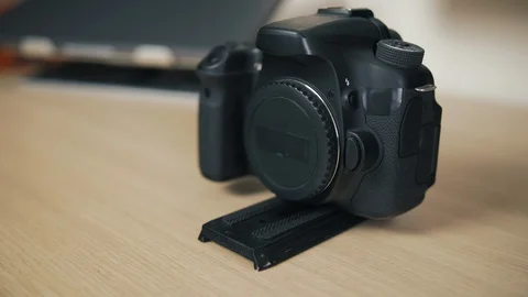 A black camera without a lens with a quick detachable plate is on a wooden table Stock Footage 129285634