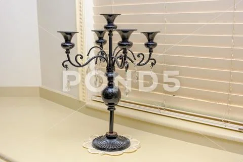 Black candlestick stands on a white windowsill Stock Photos