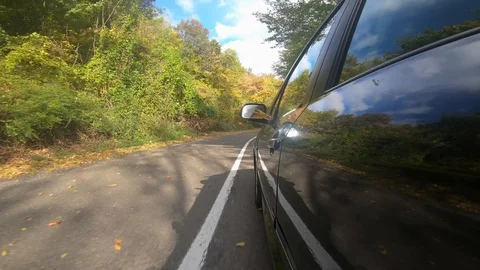 Black car driving on empty road colorful trees on autumn Stock Footage 115133451
