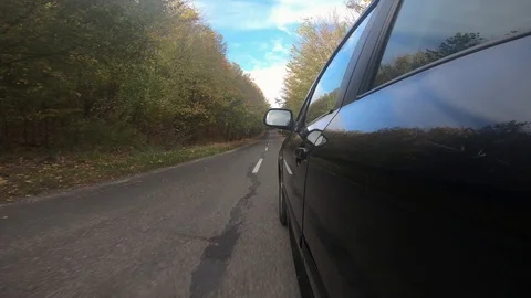 Black car driving on empty road colorful trees on autumn Stock Footage 116504884