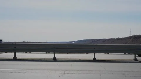 Black car driving fast on a bridge with metal railing Stock Footage 332431249
