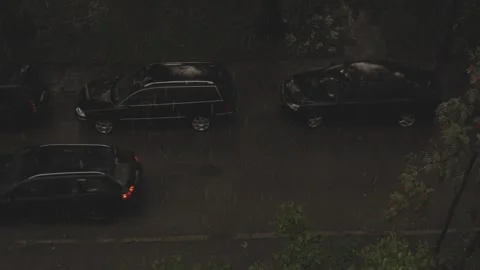 Black car driving through other parked black cars during rainfall, static Stock Footage 251870567