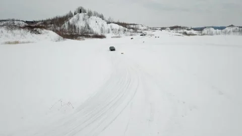 Black car rides by snowbound ice track, not far 库存影片 299633207