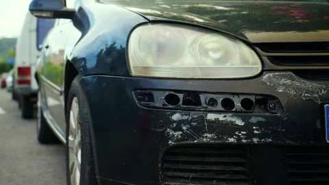 Black car showing significant front-end damage, with a broken bumper, scratched Stock Footage 339783434