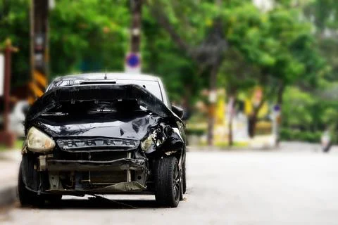 A black car with a smashed front end is parked on the side of the road Stock Photos