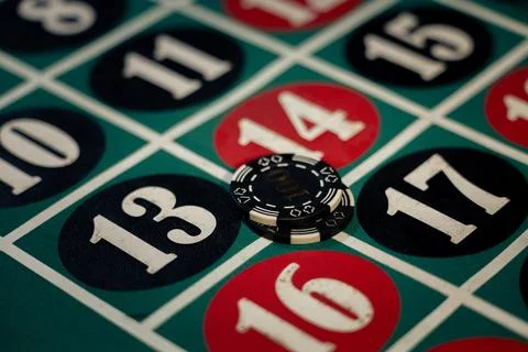 Black casino chips placed on corner bet numbers on green roulette table. Stock Photos