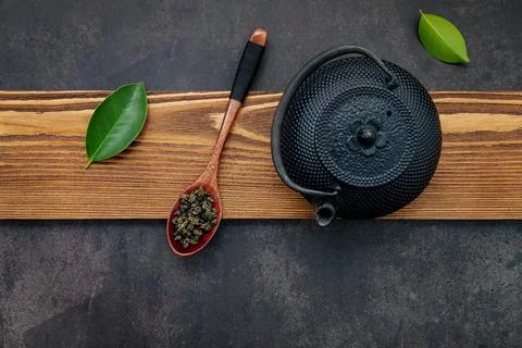 Black cast iron tea pot with herbal tea set up on dark stone background. Stock Photos