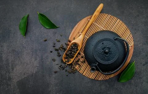 Black cast iron tea pot with herbal tea set up on dark stone background. Stock Photos