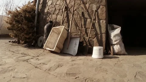 Black Cat Gets Out of Different Equipment at Wall of Garage Stock Footage 60564153