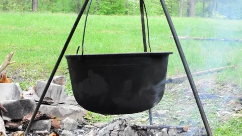 Black cauldron over open fire on background of green meadow Stock Footage 154212288