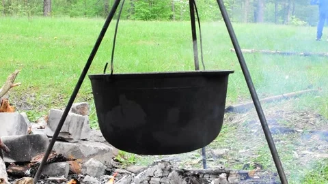 Black cauldron over open fire on background of green meadow Stock Footage 154212292