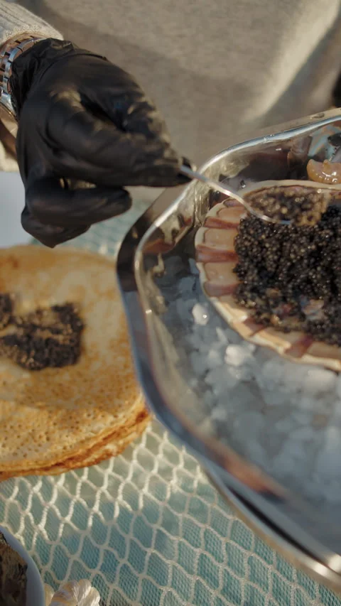 Black caviar being served onto thin pancake outdoors Stock Footage 310006914