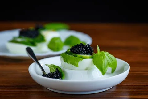 Black caviar with egg and basil on brown wooden background Stock Photos