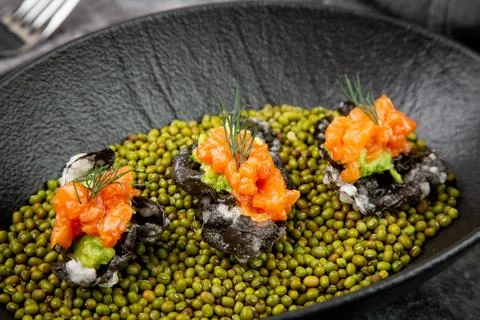 Black caviar, red fish and wassabi on a plate with peas, top view Stock Photos