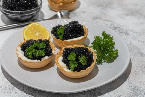 Black caviar in tartlets on a light background. Healthy food concept. Stock Photos