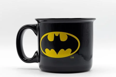 Black ceramic coffee mug featuring the yellow batman bat signal logo. Stock Photos