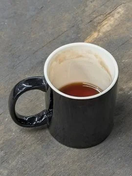 Black ceramic mug with tea on weathered wooden table Photos