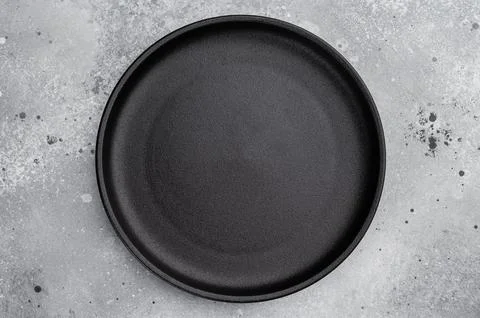 Black ceramic plate overhead on gray textured background. Elegant empty tab.. Stock Photos
